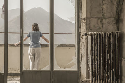 Rear view of woman standing on window