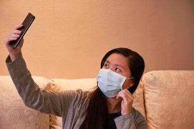Close-up of girl wearing mask taking selfie at home