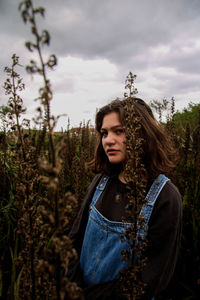 Portrait of beautiful young woman standing against sky