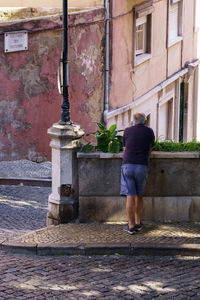 Rear view of woman standing by building