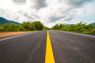 Road by trees against sky