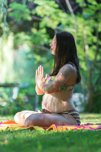 Pregnant young woman doing yoga outdoors