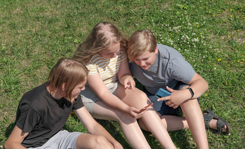 Rear view of friends sitting on grass against plants