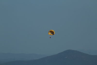 Low angle view of person paragliding against clear sky