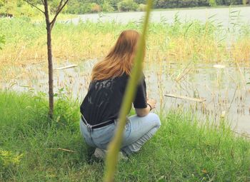 Woman sitting on grass against trees