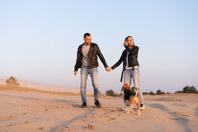 Woman with dog on street against clear sky