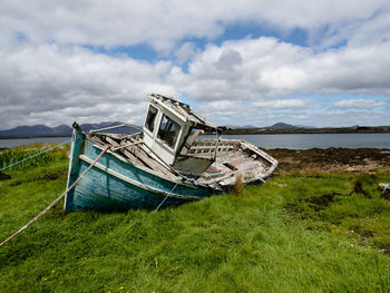 Abandoned boat moored at sea shore against sky