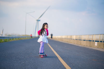 Girl standing on road against sky