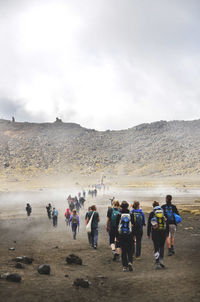 People walking on landscape against mountain range