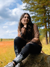 Portrait of young woman sitting on field