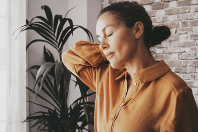 Side view of young woman standing against wall