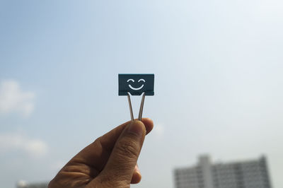 Close-up of hand holding clip against clear sky