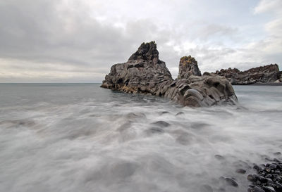 Rock formation in sea against sky