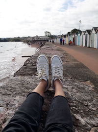 Personal perspective photo of feet with the beach on one side and colourful beach huts on the other.