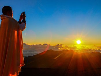 Sun shining through clouds over mountains