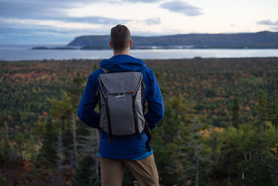 Rear view of man walking on landscape against sky