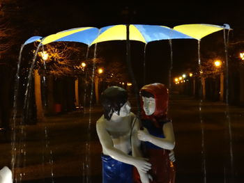 Full length of woman holding umbrella at night