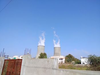 Smoke emitting from factory against blue sky