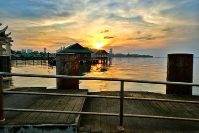 Sea by buildings against sky during sunset