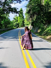 Woman standing on road against trees