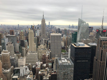 Aerial view of buildings in city against cloudy sky