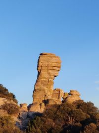 Low angle view of rock formation against clear blue sky