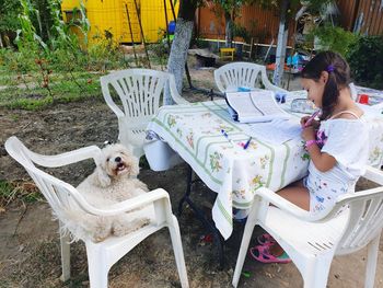 Cute girl with dog on chair in yard