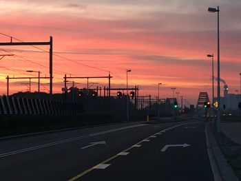 Empty road in city against sky during sunset
