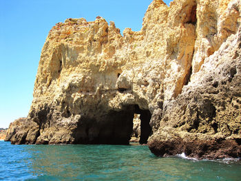 Rock formations by sea against clear sky