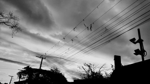 Low angle view of silhouette electricity pylons against sky at dusk