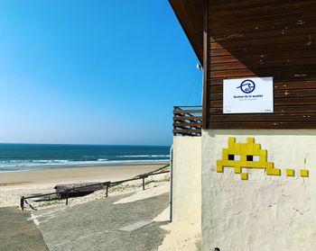 Information sign on beach against clear blue sky