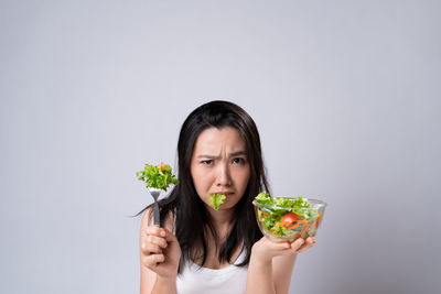 Portrait of woman holding ice cream against white background