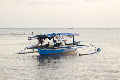 The blue fishing boat on sea against sky