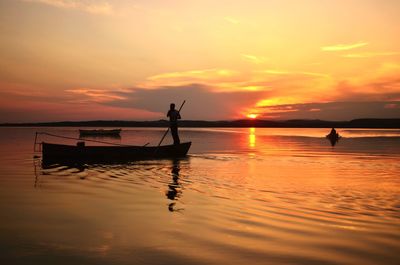 Silhouette person in sea against sky during sunset