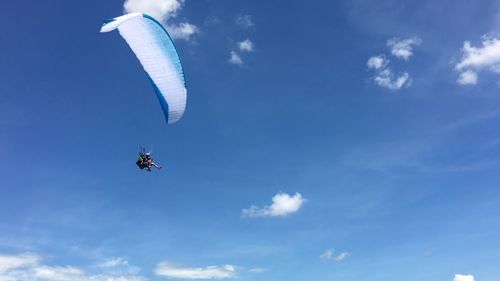 Low angle view of paragliding against blue sky