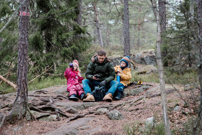 Dad sitting having a picnic with his kids whilst hiking in winter