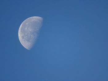 Low angle view of half moon against clear blue sky