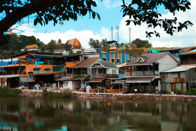 Buildings by lake against sky in city