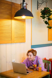 Smiling young woman using laptop at home