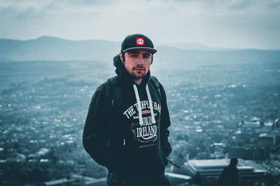 Portrait of man standing in city against sky