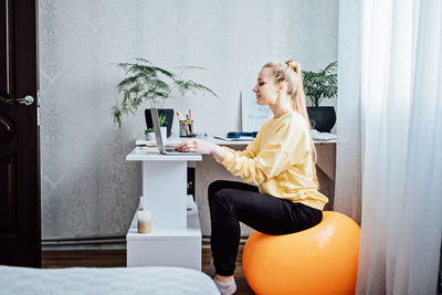 Sitting on gym ball at work. use exercise ball like chair at workplace. freelancer woman sitting on