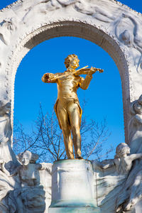 Low angle view of angel statue against blue sky