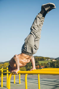 Full length of man exercising against sky