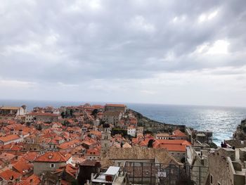 Aerial view of townscape by sea against sky