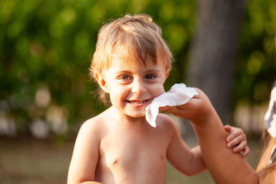 Portrait of shirtless boy holding baby outdoors