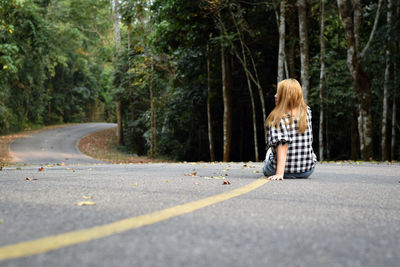 Rear view of woman on road amidst trees