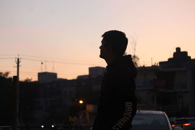 Side view of silhouette man standing against sky during sunset