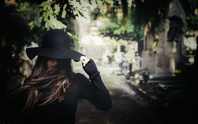 Woman with long hair wearing hat at cemetery