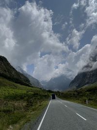 Road leading towards mountains against sky