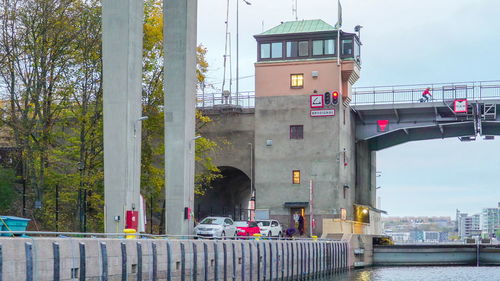 Bridge over river by buildings in city against sky